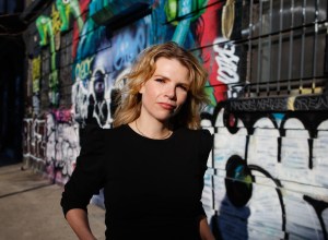 A photo portrait of Samantha Cole standing outside in front of street art